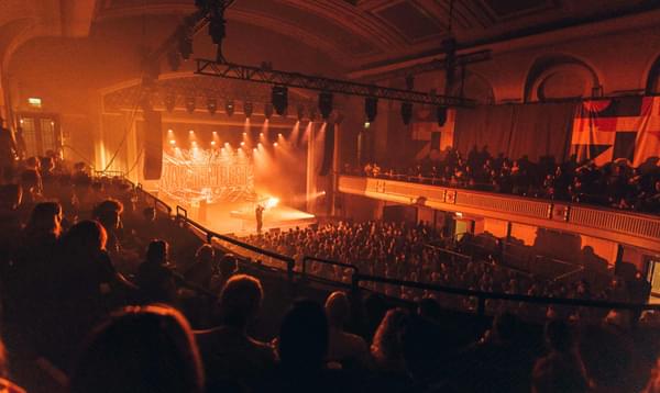 A full theatre lit up by the blow of warm yellow stage lights
