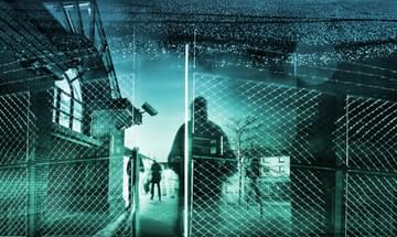 Shadowy figures stand behind  barbed wire fence, with a turquoise overcast.