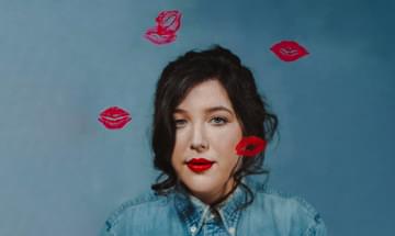 The singer pictured wearing a blue denim shirt and red lipstick, with lipstick kisses superimposed over her face and the middle of the image.