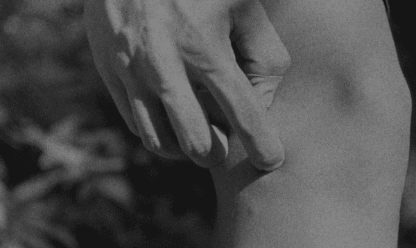Close up image of someone scratching their own leg (black & white, grainy)
