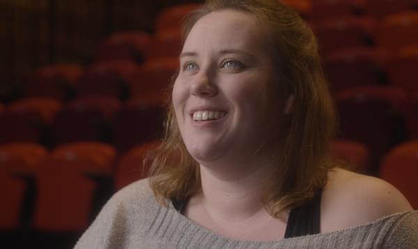 Sarah Grant sitting in a cinema smiling and looking at the cinema