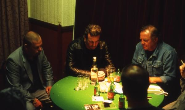 Group of men sit round poker table drinking whisky