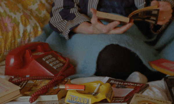 Grainy close up shot of a cluttered coffee table with a bright red, landline phone.