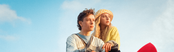Actors Louis McCartney and Ella Lily Hyland sit on rock looking into distance in Silent Roar.