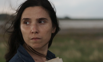 Laura Paredes stands in a field clutching papers to her chest.