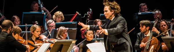 Maxim Emelyanychev stands in the centre of the Scottish Chamber Orchestra, dynamically conducting