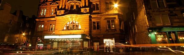 Outside of Edinburgh's Kings' Theatre light up at night with lights of cars passing by
