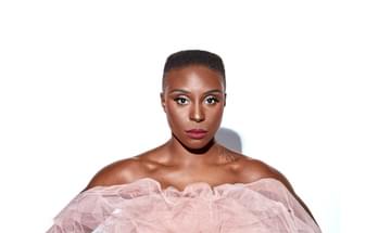 Laura Mvula pictured standing against a white background, wearing a pink tulle strapless dress.