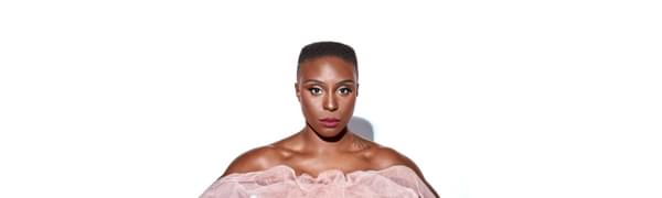 Laura Mvula pictured standing against a white background, wearing a pink tulle strapless dress.