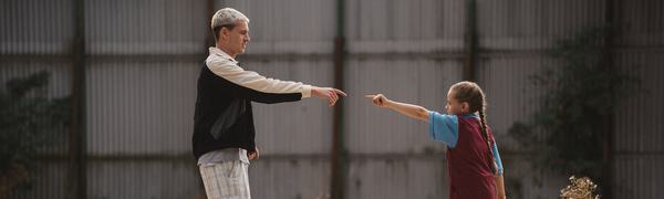 An older teen boy pointing at a young tween girl