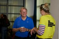 A man in a blue polo shirt holds a mug and smiles at a woman with blonde hair in a yellow Festival t-shirt