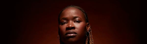 Adura Onashile looks directly at the camera with a soft halo of light behind her.