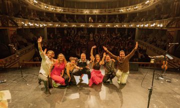 A group of people on stage, in a packed auditorium