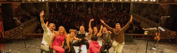 A group of people on stage, in a packed auditorium