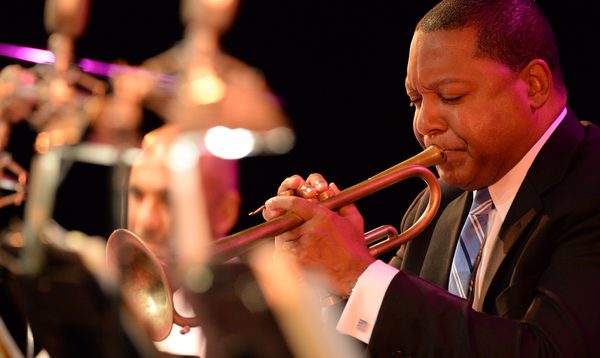 A man plays trumpet with his eyes closed as part of an orchestra