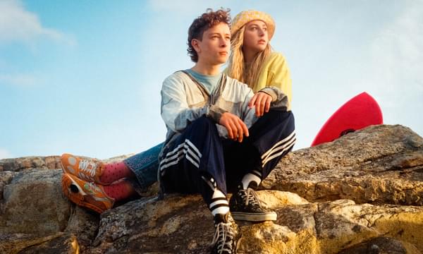 Still from Silent Roar, featuring teenage boy and teenage girl sitting on a rock and looking out to a sunset